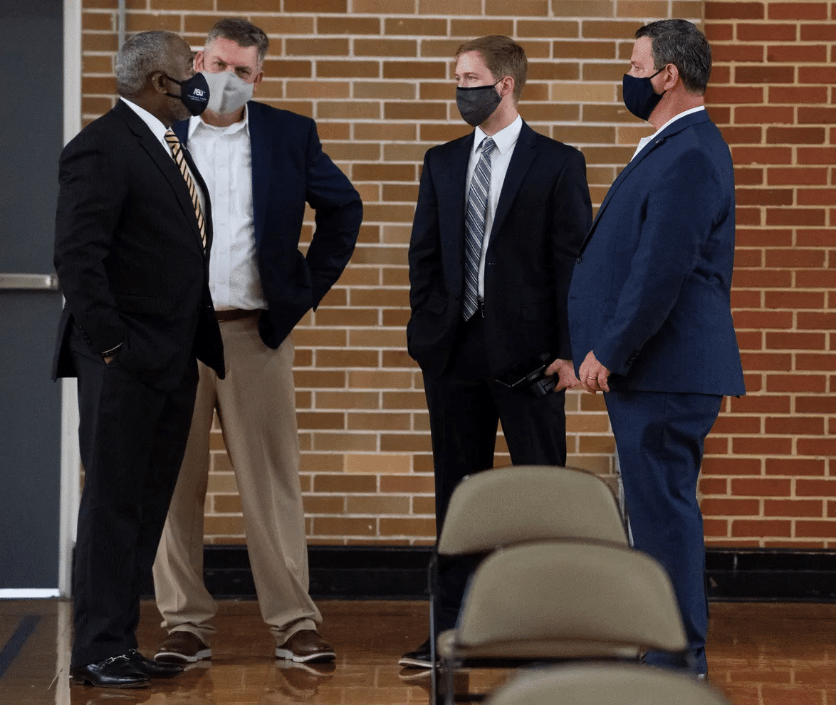 a group of people standing next to a man in a suit and tie